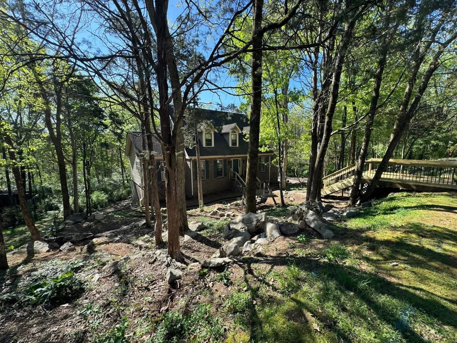 Wooded residential property after selective clearing revealed the home, stone and circulation