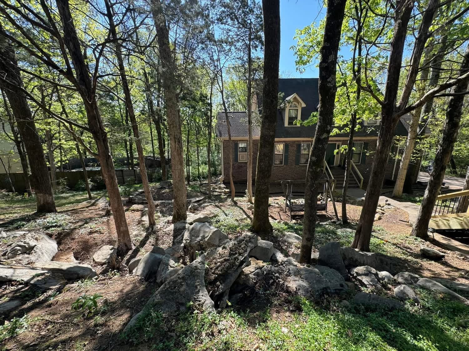 Restored woodland with the home, mature trees and natural stone visible through the site